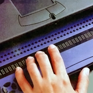 Jemand liest auf einer Braillzeile (Nahaufnahme der Hand und der Braillezeile).